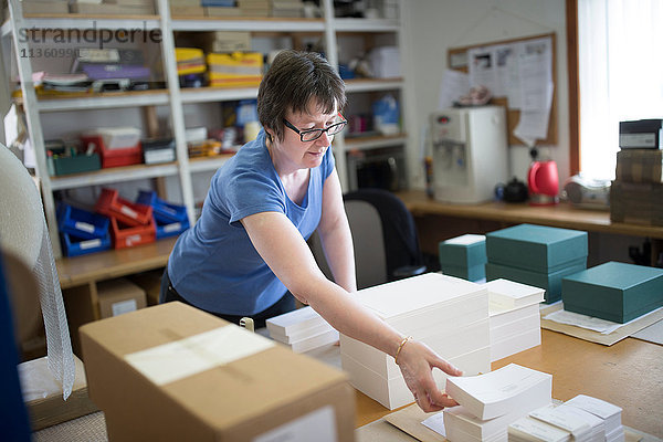 Arbeitnehmerin verpackt gestapeltes Papier in Druckereiwerkstatt
