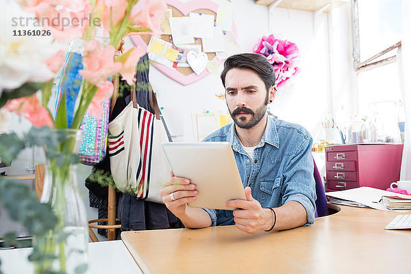 Junger männlicher Designer liest digitale Tablette im Druckmaschinenstudio