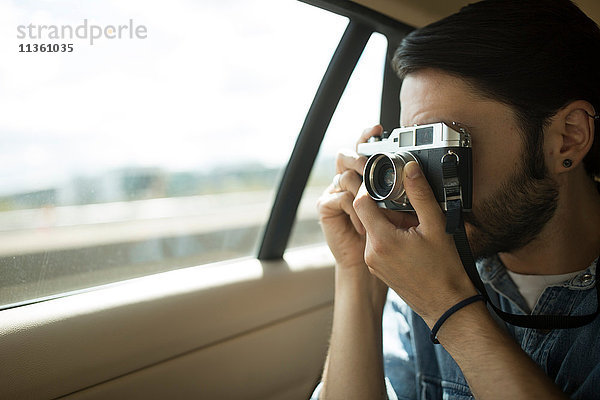 Junger Mann unterwegs  der durch ein Autofenster fotografiert