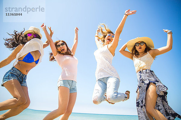 Vier erwachsene Freundinnen springen am Strand in die Luft  Malibu  Kalifornien  USA