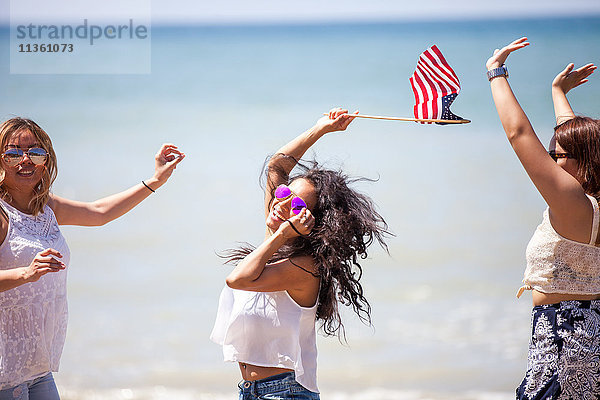 Drei erwachsene Freundinnen schwenken die amerikanische Flagge am Strand  Malibu  Kalifornien  USA