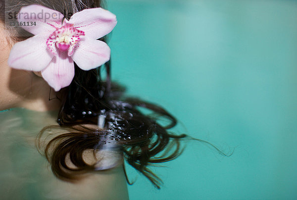 Schnappschuss einer Frau im Whirlpool mit violetter Orchidee im Haar