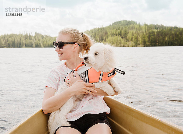 Frau hält Hund coton de tulear im Boot  Orivesi  Finnland