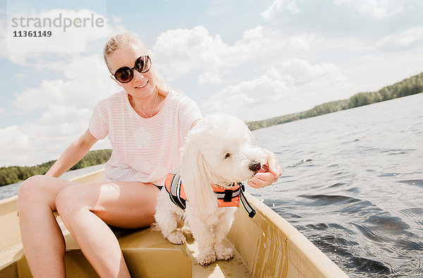 Frau streichelt coton de tulear Hund im Boot  Orivesi  Finnland