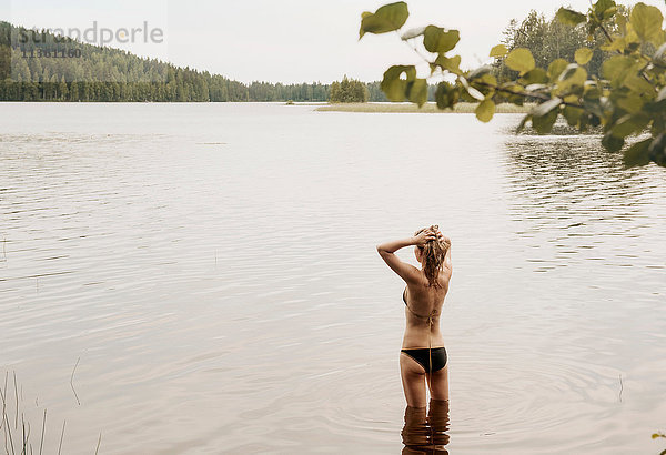 Rückansicht einer Frau mit Händen im Haar im See  Orivesi  Finnland