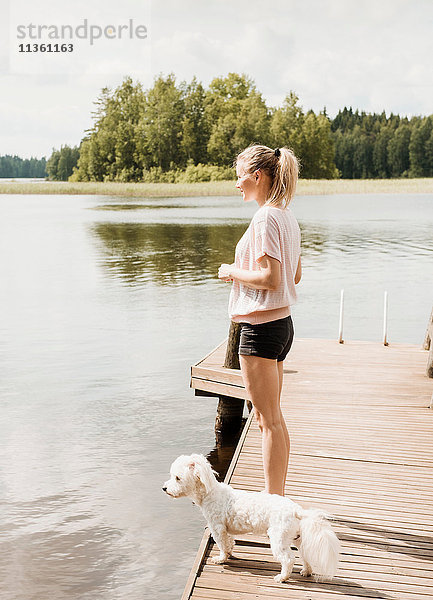 Frau steht mit dem Hund Coton de tulear am Seepier  Orivesi  Finnland