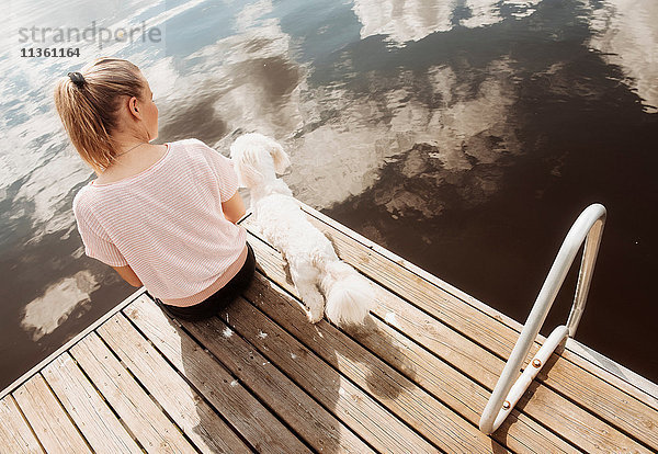 Frau sitzt mit dem Hund Coton de tulear am Seepier  Orivesi  Finnland