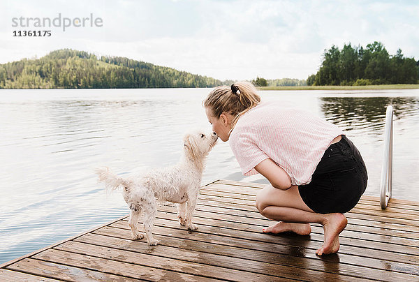 Frau küsst coton de tulear Hund auf dem Pier  Orivesi  Finnland