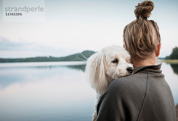 Coton de tulear Hund schaut über die Schulter der Frau am See  Orivesi  Finnland