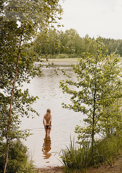 Rückansicht einer Frau  die steht und vom See aus schaut  Orivesi  Finnland