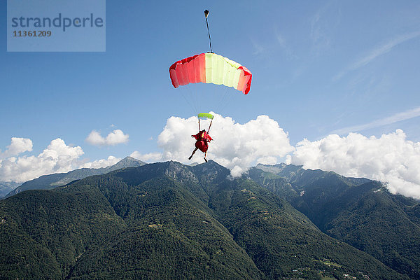 Fallschirmspringerin unter ihrem Fallschirm  die frei am blauen Himmel fliegt  Locarno  Tessin  Schweiz