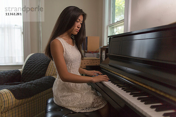 Teenager-Mädchen sitzt im Esszimmer und spielt Klavier