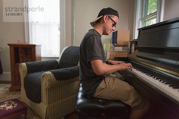 Teenager Junge sitzt im Esszimmer und spielt Klavier
