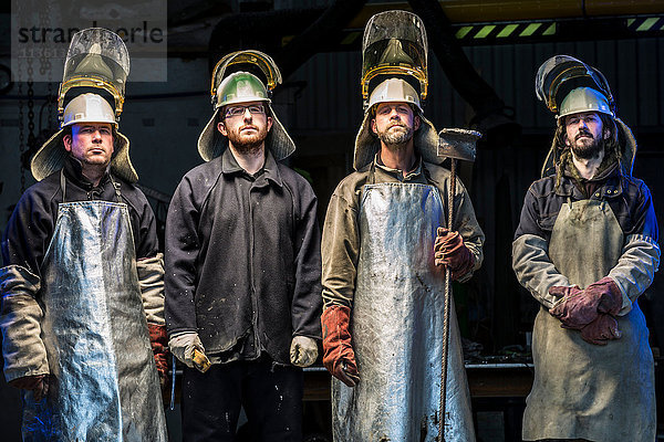 Porträt von vier männlichen Gießereiarbeitern mit Schutzkleidung in einer Bronzegießerei