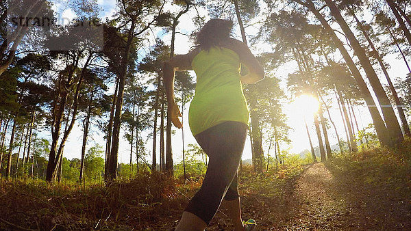 Rückansicht einer Frau  die im Wald joggt
