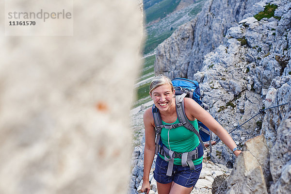 Frau wandert den Berg hinauf und schaut lächelnd in die Kamera  Österreich