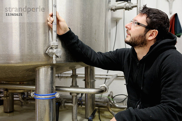 Arbeiter in einer Brauerei  Überprüfung des Manometers am Brautank