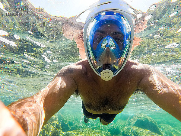 Porträt eines Mannes unter Wasser mit Schnorchel  der in die Kamera schaut