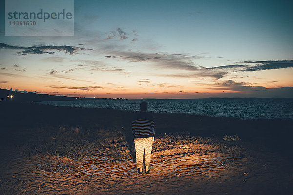 Rückansicht einer Frau am Strand mit Blick auf den Sonnenuntergang  Sorso  Sassari  Italien