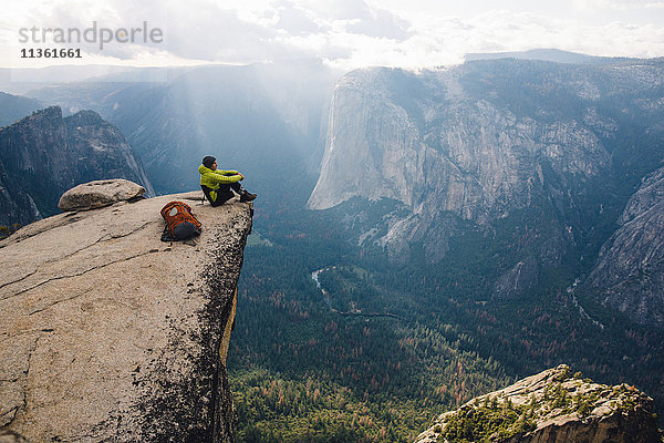 Mann sitzt auf dem Gipfel eines Berges mit Blick auf den Yosemite National Park  Kalifornien  USA