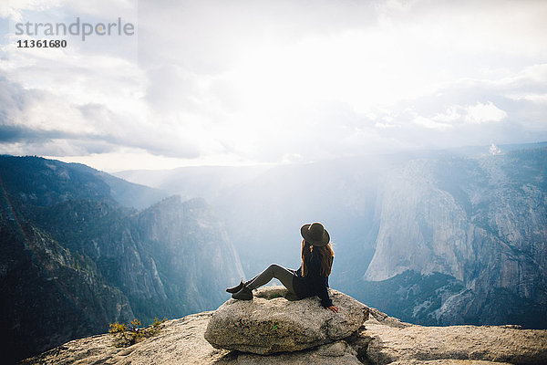 Junge Frau sitzt auf dem Gipfel eines Berges mit Blick auf den Yosemite National Park  Kalifornien  USA