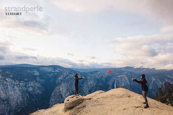Junge Frau spielt mit Flying Disc auf dem Gipfel eines Berges mit Blick auf den Yosemite National Park  Kalifornien  USA