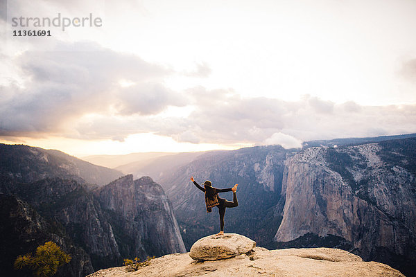 Junge Frau steht in Yoga-Pose auf dem Gipfel eines Berges mit Blick auf den Yosemite-Nationalpark  Kalifornien  USA