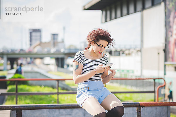 Frau im Stadtgebiet sitzend  SMS auf Smartphone  Mailand  Italien