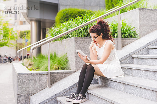 Frau auf einer Treppe sitzend mit digitalem Tablett  Mailand  Italien