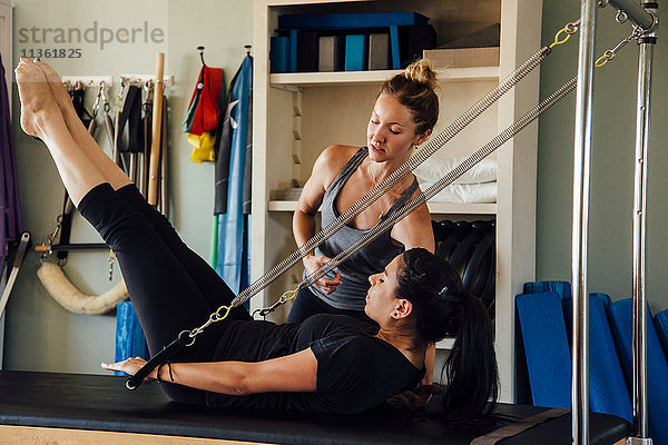 Frau und Personal Trainerin mit Pilates-Reformer