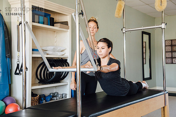 Frau und Personal Trainerin mit Pilates-Reformer