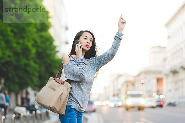 Junge Frau mit Smartphone beim Taxifahren in der Stadt