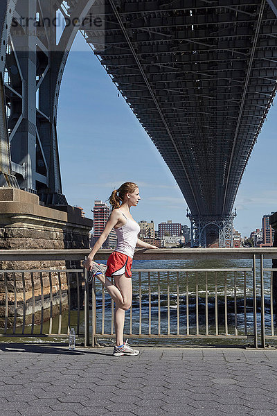 Junge Frau beim Sport im Freien  Stretching  unter der Williamsburg Bridge  New York City  USA