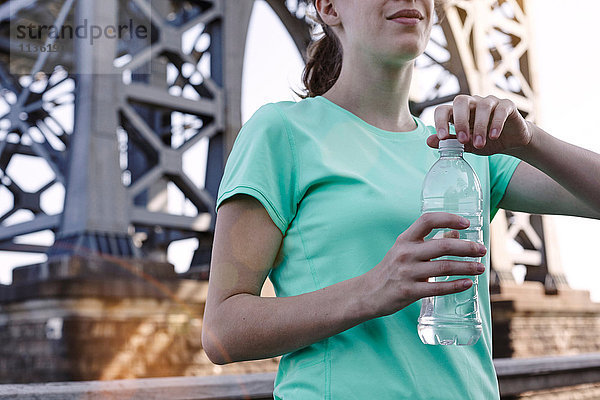 Junge Frau im Freien  eine Wasserflasche haltend  Mittelteil  New York City  USA