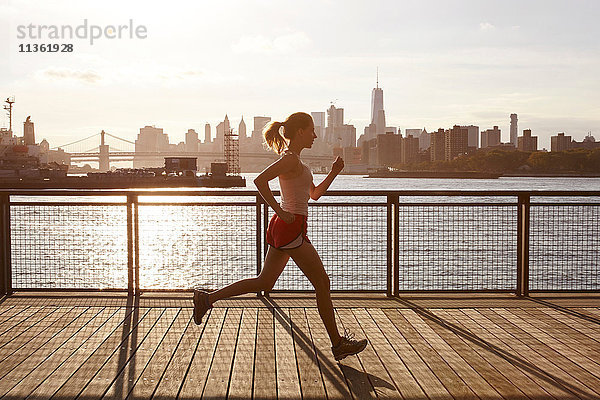 Seitenansicht einer Frau  die auf dem Pier joggt  Manhattan  New York  USA
