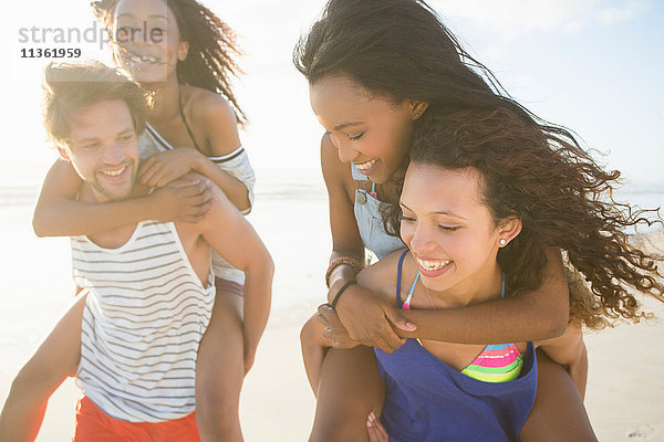 Junge Männer und Frauen nehmen Freunde am Strand huckepack  Kapstadt  Südafrika