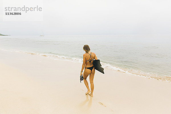 Schwimmer mit Schwimmflossen  am Strand spazieren