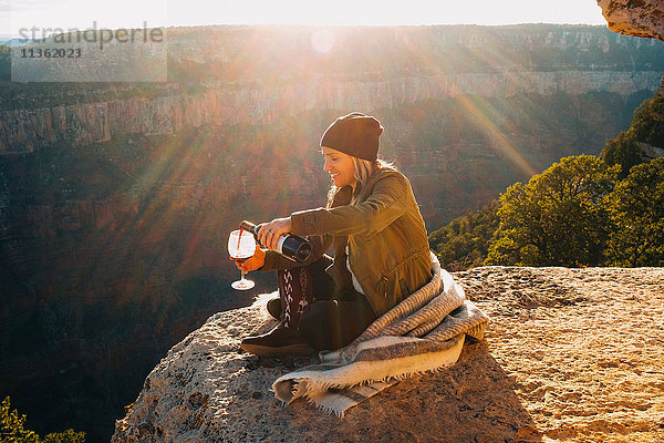 Frau schenkt ein Glas Wein am Rand des Grand Canyon ein  Arizona  USA