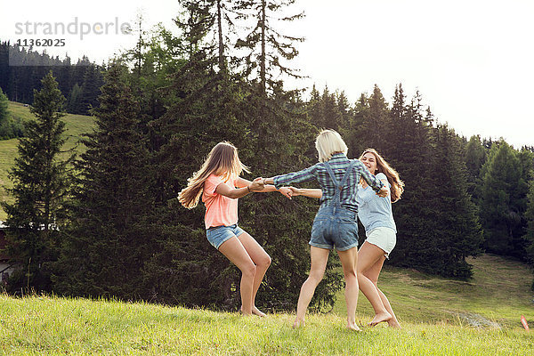 Drei erwachsene Freundinnen spielen Ring-a-rosie im Feld  Sattelbergalm  Tirol  Österreich