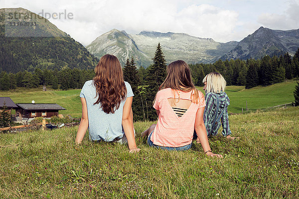 Rückansicht von drei erwachsenen Freundinnen mit Blick auf die österreichischen Alpen  Sattelbergalm  Tirol  Österreich