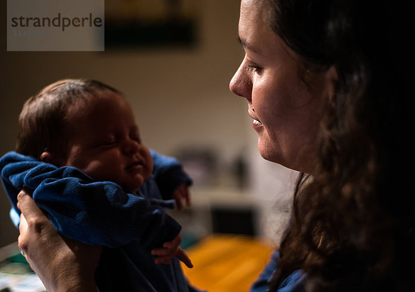 Mutter wiegt neugeborenen Sohn in der Küche