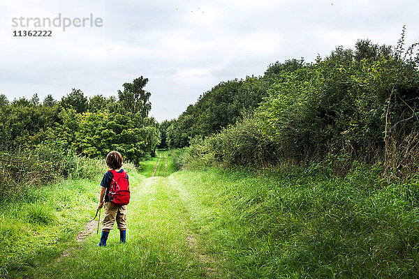 Rückansicht eines Jungen mit Rucksack auf ländlicher Landschaft