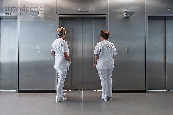 Rückansicht der auf den Aufzug wartenden Krankenschwestern im Krankenhaus