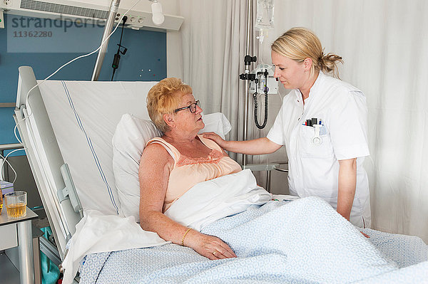 Krankenschwester  die den Patienten im Krankenhausbett pflegt