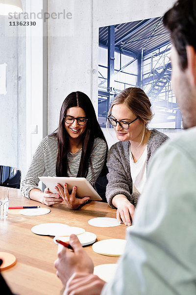 Kollegen bei Besprechung im Konferenzraum mit digitalem Tablet