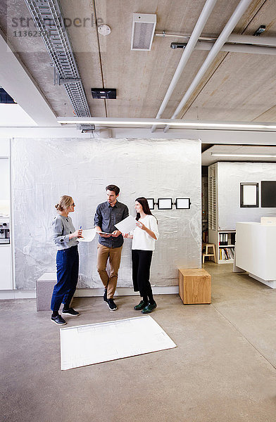 Architekten im Büro diskutieren über Entwürfe