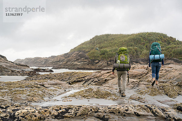 Junges Paar beim Trekking über Gezeitenbecken  Rückansicht  Constant Bay  Charleston  Südinsel  Neuseeland