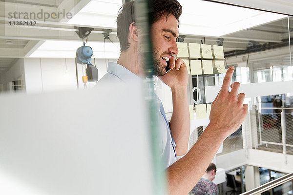 Geschäftsmann im Büro mit Mobiltelefon