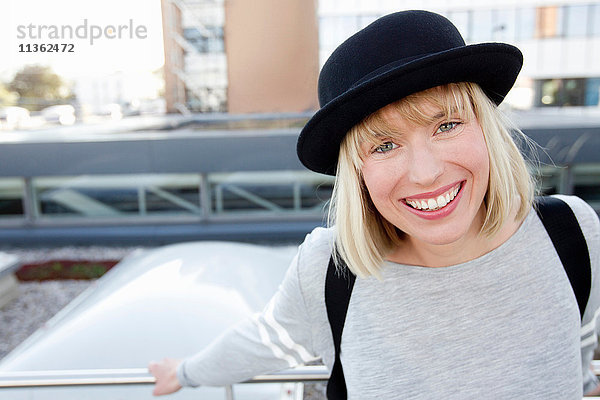 Porträt einer blondhaarigen Frau mit Hut  die lächelnd in die Kamera schaut