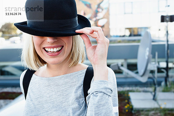 Porträt einer blondhaarigen Frau mit Hut über lächelnden Augen